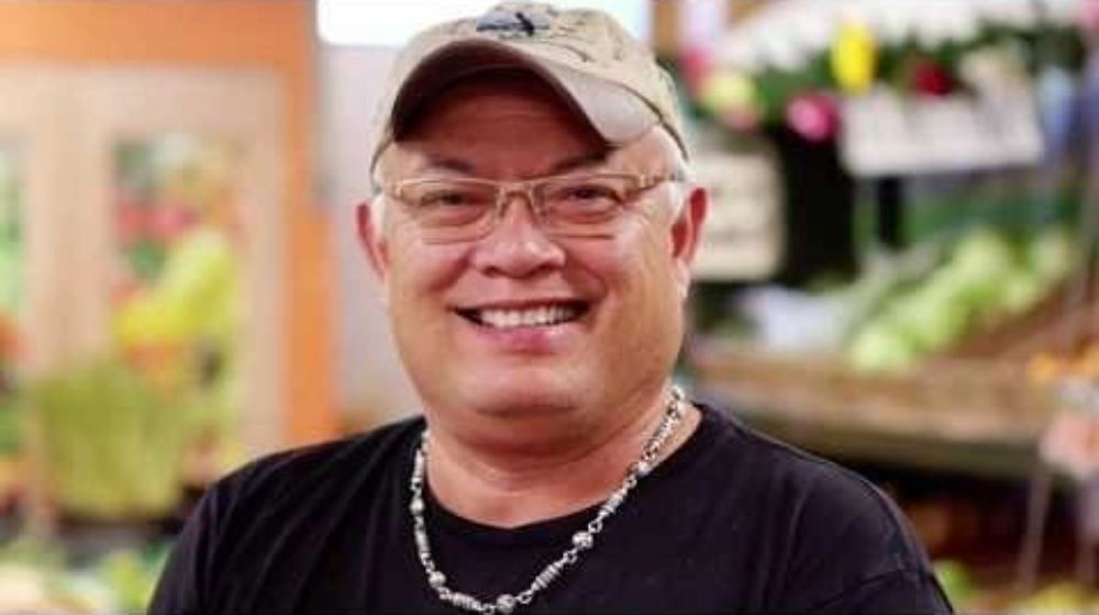 A man wearing glasses and a hat smiling for the camera.