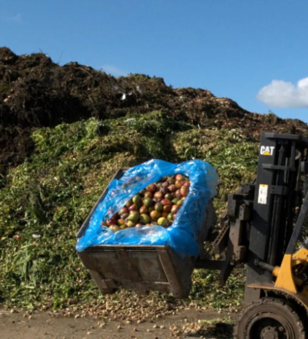 A large container of apples is being loaded on to the back of a truck.