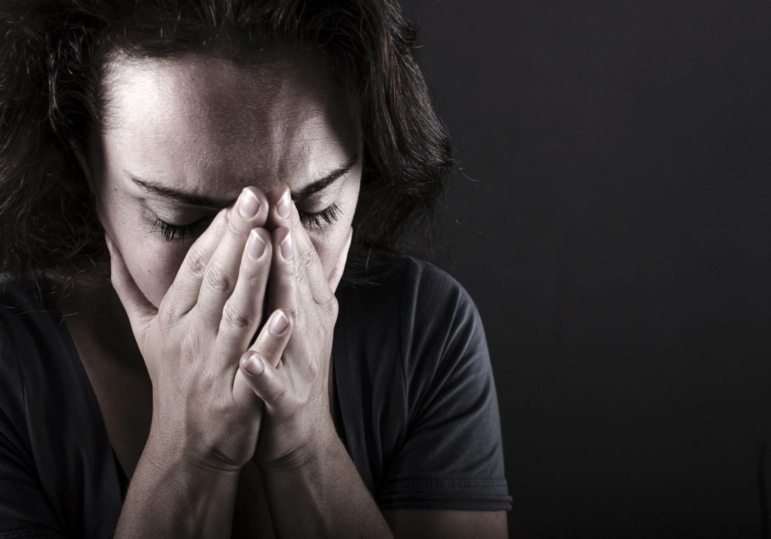 A woman is holding her hands to her face.